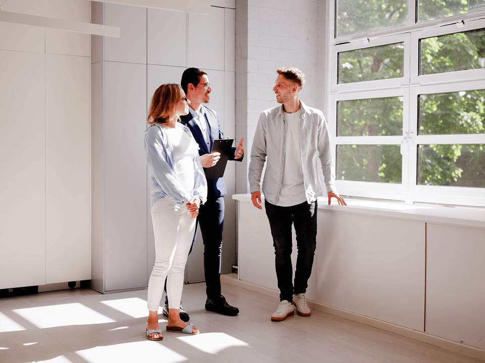 People viewing a sunlit room with realtor.